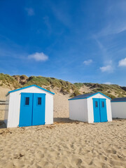 Bright blue beach huts stand against a sandy landscape under a clear skyin Texel Netherlands