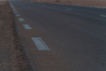 an asphalt road leading through a flat section of desert
