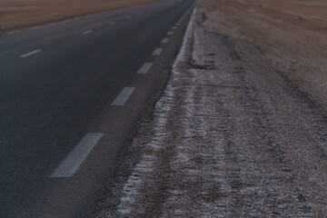 an asphalt road leading through a flat section of desert