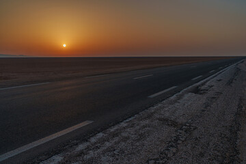 View of the asphalt road running through the desert at sunset