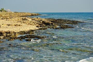 A beautiful rocky shoreline in Ayia Napa, Cyprus, with clear Mediterranean waters, sandy patches, and a serene coastal horizon