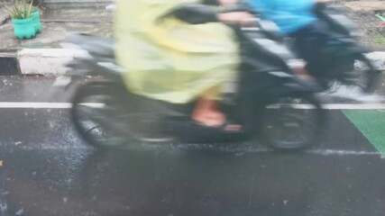 Motorbikes pass through the wet asphalt road during heavy rain. A view from behind a window glass, inside the car. - Powered by Adobe