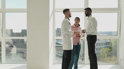 Doctor and indian family couple patients communicate in hospital corridor. Doctor stands in hospital hallway with worried asian husband and wife. - Powered by Adobe