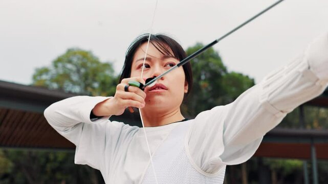 Archery, sports and Asian woman with bow in field for training, target practice and shooting competition. Drawing, anchor point and person with arrow for challenge, tournament or performance in Japan