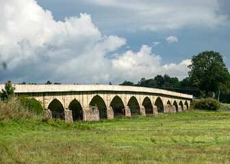 arched bridge over the river, historic bridge, green landscape from summe