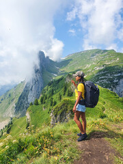 Captivating hiker gazing at majestic mountain landscape under a cloudy sky in summer