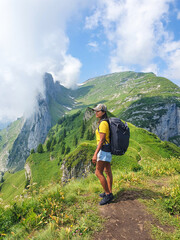 Obraz premium Hiking through majestic mountain on a sunny day with lush greenery and dramatic clouds in Swiss Alsp