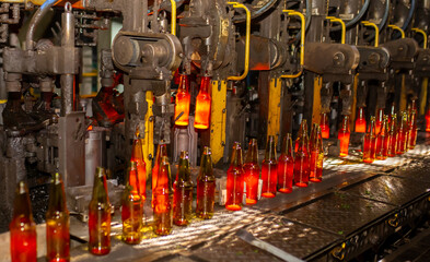 Glass factory, production of glass containers. Molten glass is blown into molds. Robotics in industry. Modern technologies, robotic machines produce products. Technological work at the plant.