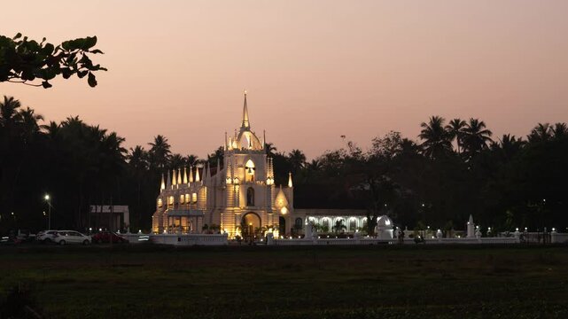 4K Timelapse footage of the Neo-Gothic Mae de Deus Catholic church in Saligao Goa at dusk night with traffic light trails and illuminated church and people visiting the church