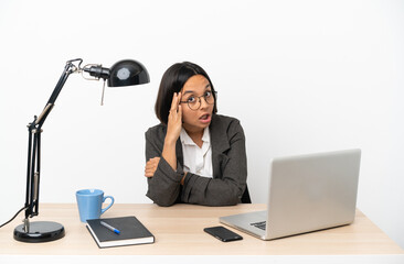 Young business mixed race woman working at office doing surprise gesture while looking to the side