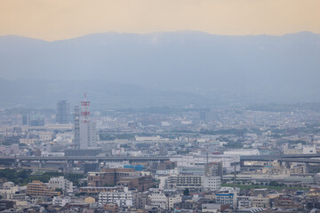 Fototapeta premium A serene view of Kyoto, showcasing the city’s sprawling urban layout under a soft, pastel sky. The image highlights a blend of modern infrastructure and distant hills that gently embrace the cityscape