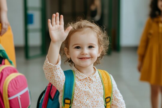 Toddler waves goodbye, a sweet farewell, backpack adorns her back, radiating joy.
