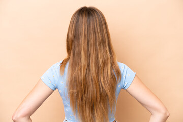 Fototapeta premium Young caucasian woman isolated on beige background in back position