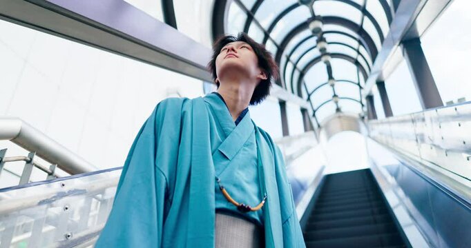 Man, thinking and escalator in city for travel, journey and kimono for Japanese fashion. Asian person, below and lift in airport with indigenous style, heritage pride or culture attire in urban Tokyo