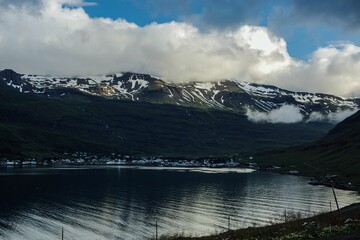 Obraz premium Coastal town beneath snow-capped mountains