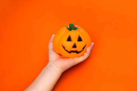 Child's hand holding a Halloween pumpkin