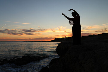 Woman practicing yoga on the beach at sunset