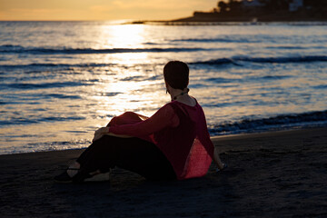 Woman practicing meditation at sunset on the beach