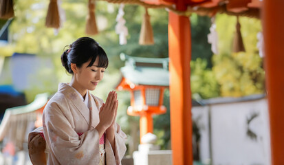神社で手を合わせる着物の日本人女性