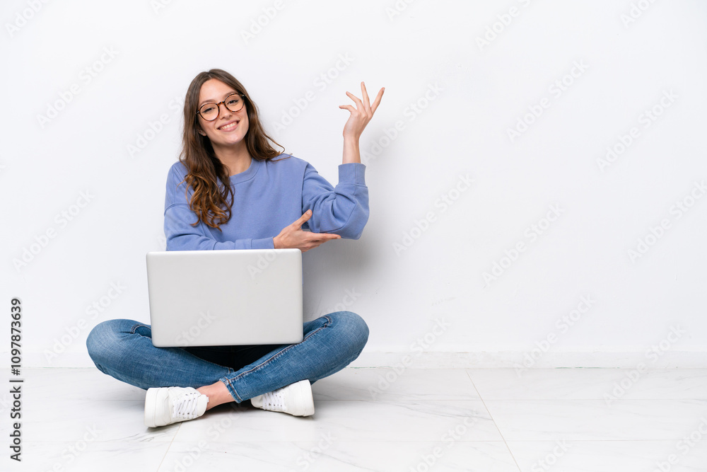 Canvas Prints Young caucasian woman with a laptop sitting on the floor isolated on white background extending hands to the side for inviting to come