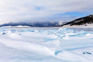 Winter landscape of frozen Baikal Lake. View from ice with snow-covered hummocks of blue ice floes...