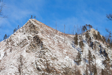 Winter landscape with snow-capped peaks of rocky mountains near Goloustnaya River on sunny January...