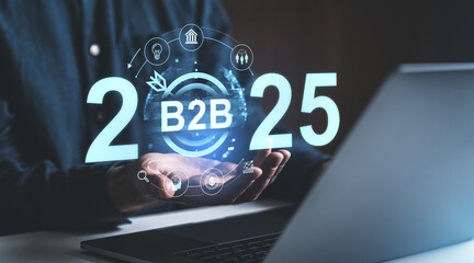 Businessman holding virtual hologram displaying B2B 2025 with futuristic icons, suggesting future business strategy and forecast concept.