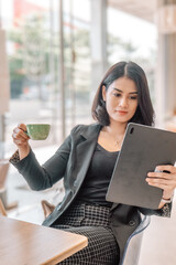 A beautiful career woman, wearing a black blazer suit, is at a cafe. 