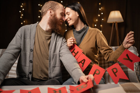 Couple in love preparing decorations for birthday party in the living room at night