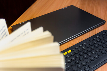 Flat lay of a notebook, a bluetooth keyboard and a computer on a wooden desk. Working from home and...