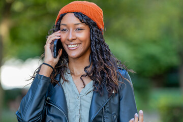 young latina woman talking on mobile phone on the street with hat and urban style