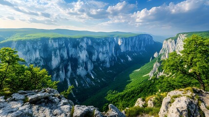 Fototapeta premium Stunning panoramic view of a green valley surrounded by towering cliffs and blue skies.