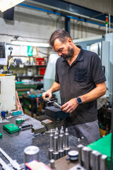 Worker using micrometer to measure metal pieces in cnc factory
