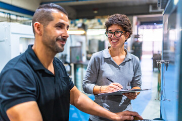 Worker talking with female manager while using computer in the factory