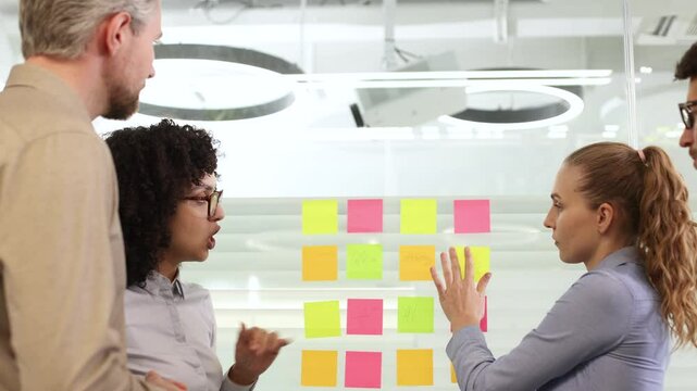 Creative group or business people planning innovation with sticky notes on glass wall.