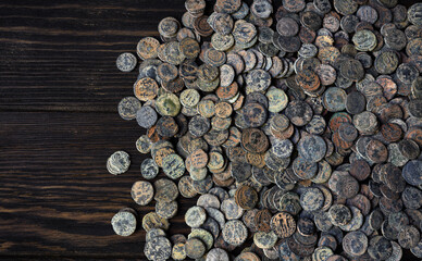 Lot of Ancient Roman coins on old dark wooden table, top view of pile of bronze money, vintage...