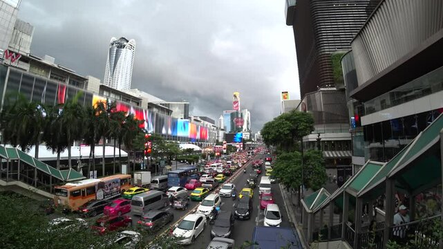 BANGKOK, THAILAND - AUGUST 2024 : Aerial high angle view of busy traffic around downtown shopping area in daytime. Transportation and street traffic concept video.