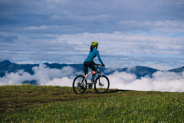 Obraz premium Asian woman riding mountain bike on beautiful mountain top