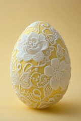 Fototapeta premium This Easter egg displays an elegant lace overlay pattern in white, with detailed bees and flowers on a yellow background