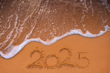 Happy New Year 2025 concept, lettering on the beach sand and sea wave