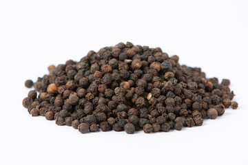 Granos enteros de pimienta negra en primer plano, con textura rudosa y tonalidades oscura, sobre fondo blanco
