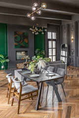 Close-up of a chic luxury dining table in a dark brutal interior in a historical style in a mansion with panoramic windows. grey-green walls and brown parquet