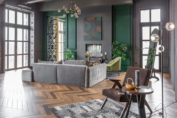 the dark brutal interior of the living room in a historical style in a mansion with panoramic windows. grey-green walls, brown parquet and modern furniture.