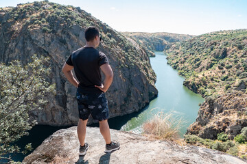 Jovem Turista a contemplar os penhascos e um pequeno barco a passar no rio Douro Miradouro em Miranda do Douro, Portugal