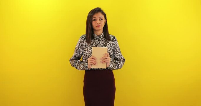 Beautiful young woman reading book, feeling stressed closed eyes and looking on yellow background.