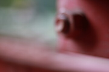 A dreamy view of a repeating pattern on a bright red metal structure with a bolt detail.