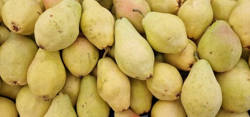 Yellow juicy pears displayed in a pile for sale in a vegetable market