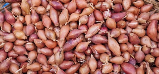 many small onions lying in a pile for sale