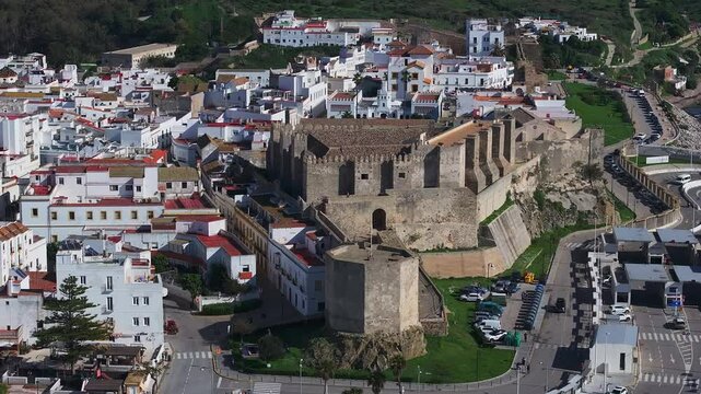 Aerial view of Tarifa's whitewashed buildings, Castillo de Guzman, and the Strait of Gibraltar with Morocco visible across the water.