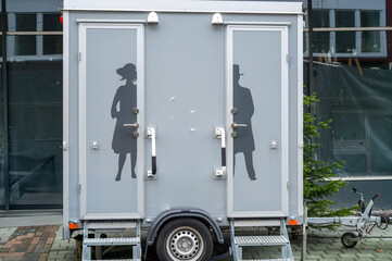 Mobile toilet trailer displaying gender symbols for men and women restrooms
